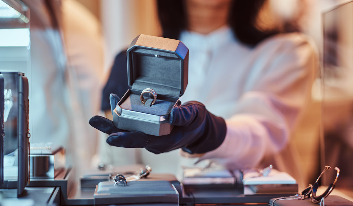 Woman assistant shows the exclusive gold ring in the jewelry store