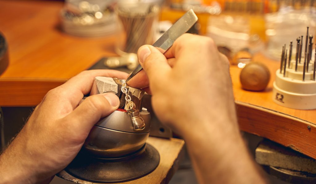 Male hands using a tool for stone setting 