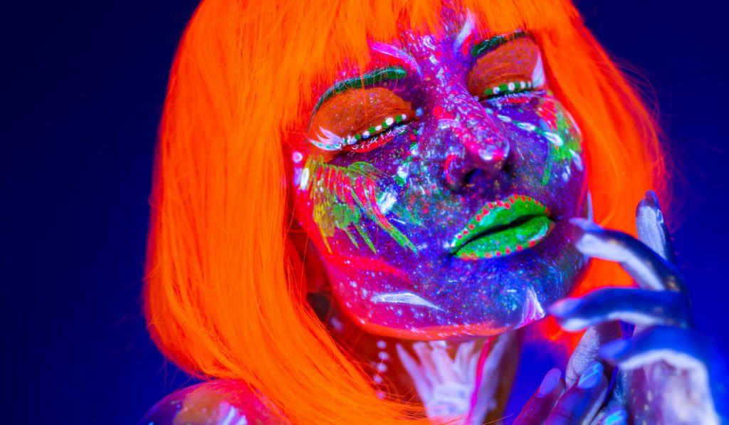 Portrait of woman in with neon makeup.