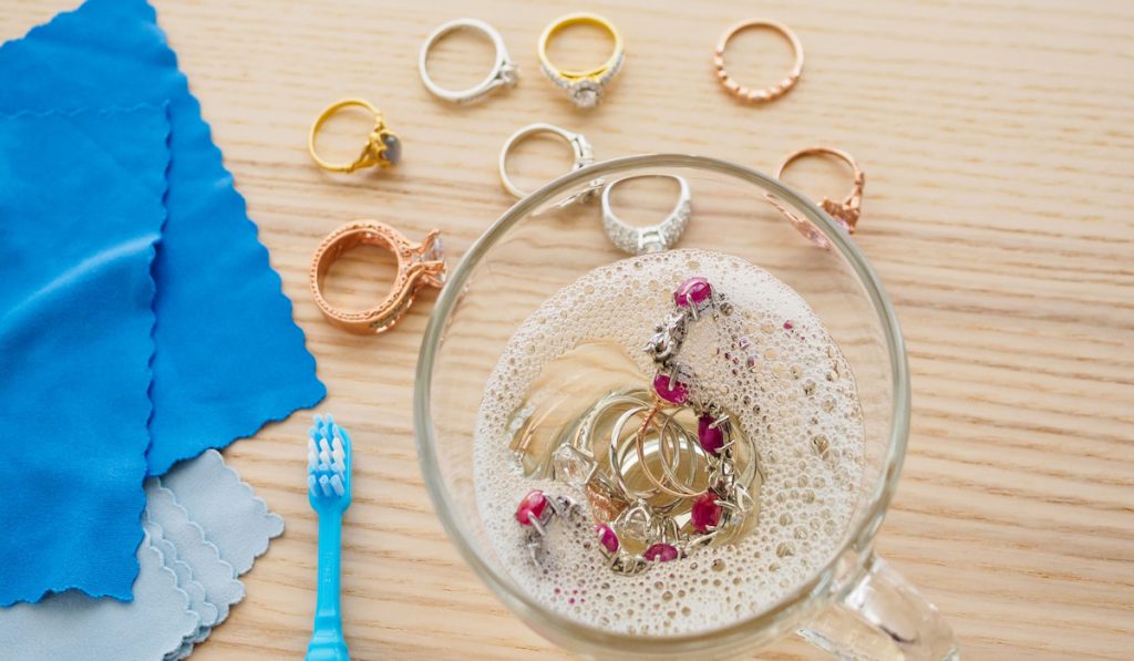 cleaning process of jewelries in a bowl with toothbrush and soft cloth 