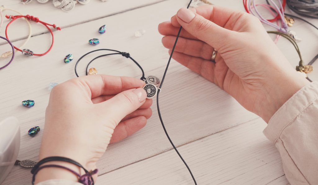 hand of a woman making handmade jewelry on the table