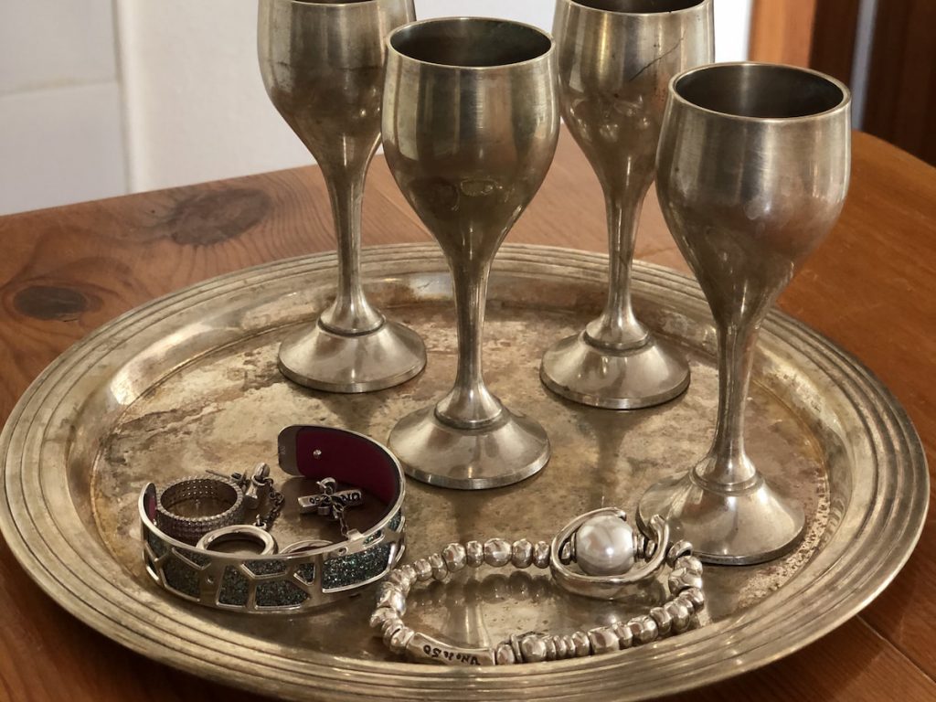 women's Silver jewelry on a silver tray with glasses on a high leg